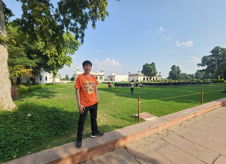A person standing on a sidewalk with a large tree and a building in the background. 4