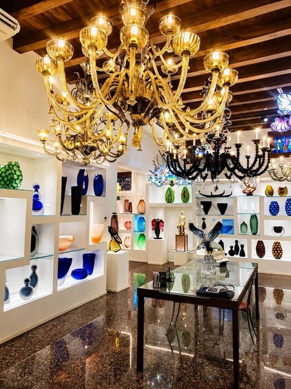A modern interior with a large golden chandelier, glass display shelves, and a marble floor. 3