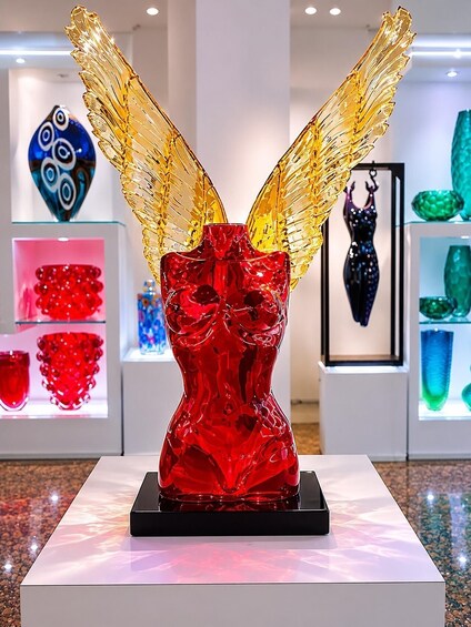 A glass sculpture with wings on a pedestal in an art gallery. 5