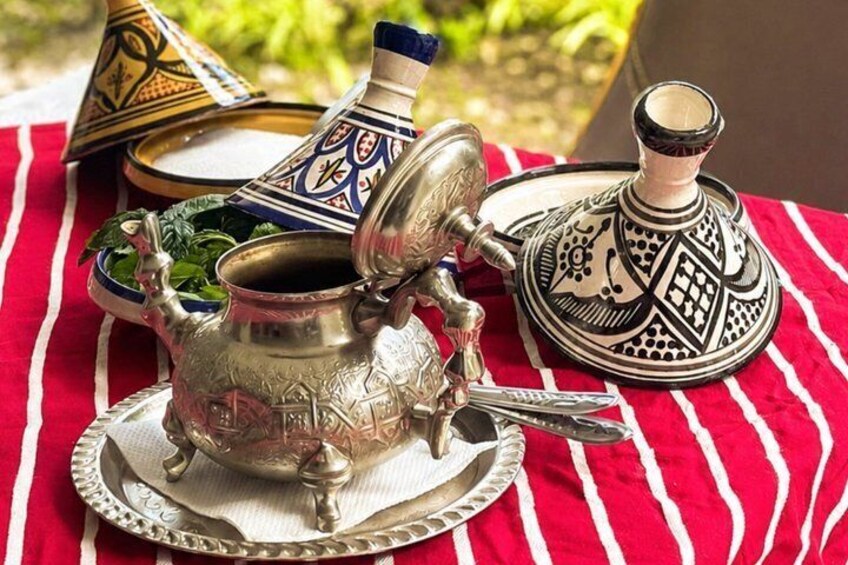 A traditional Moroccan tea set with ornate metalwork, a striped red and white cloth, and a patterned blue and white teapot. 5