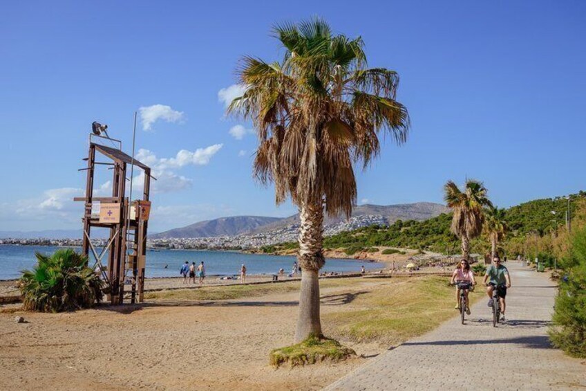 A beach with palm trees, a lifeguard tower, and a path with cyclists. 5