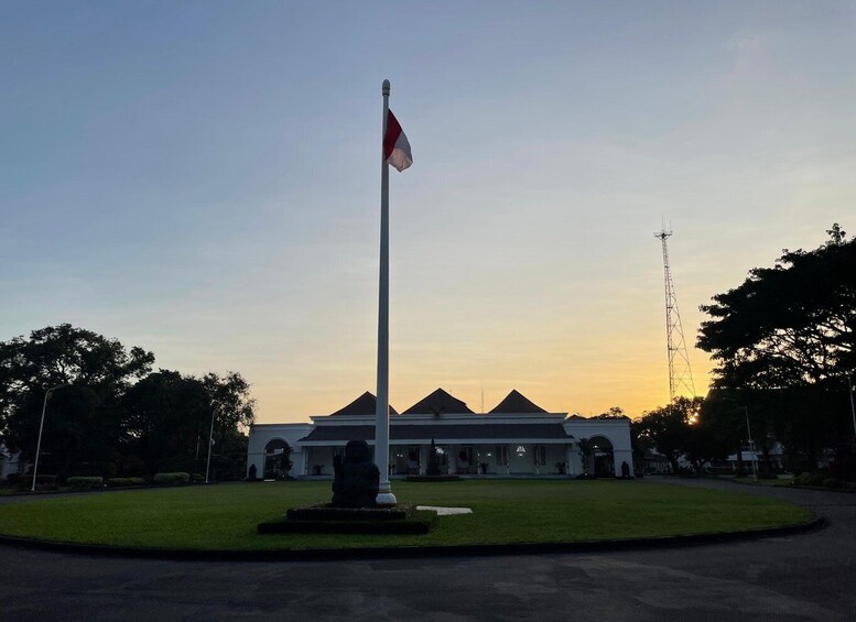 A flagpole with a flag, a building with a triangular roof, and a transmission tower. 2