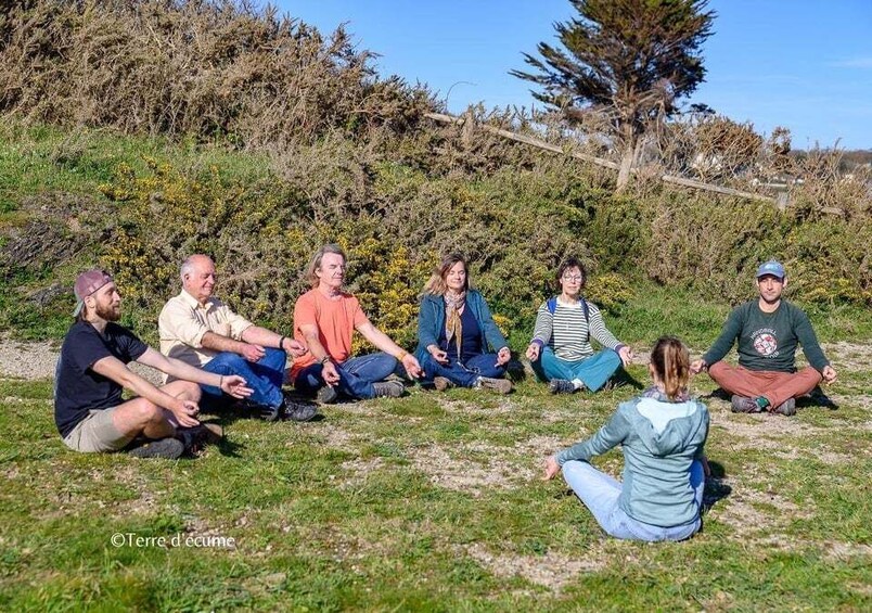 A group of people sitting in a circle outdoors on grass. 5