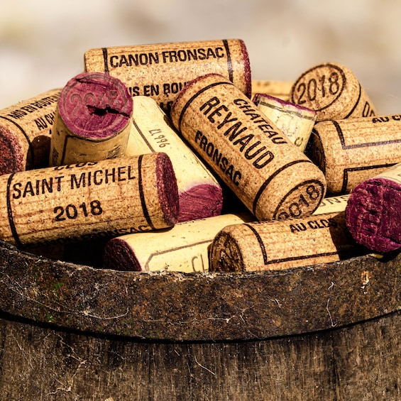 A wooden container filled with wine corks labeled with names and years. 2
