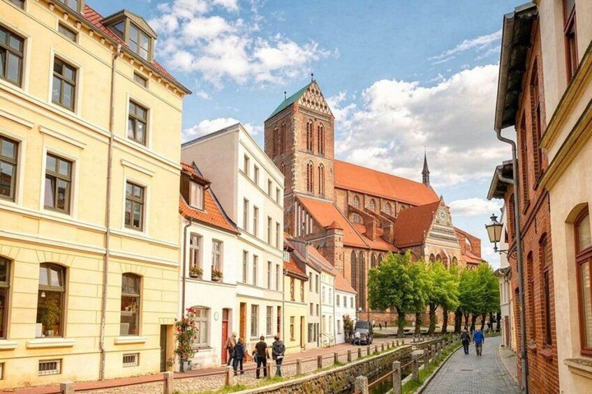 A street with historic buildings, a church, and a pedestrian walkway. 4