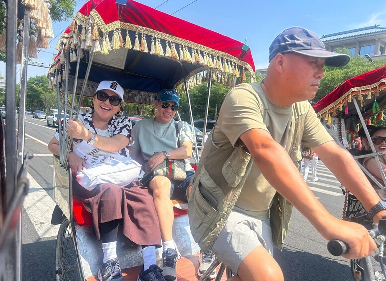 A group of people on a horse-drawn carriage with a red canopy, traveling on a street. 4