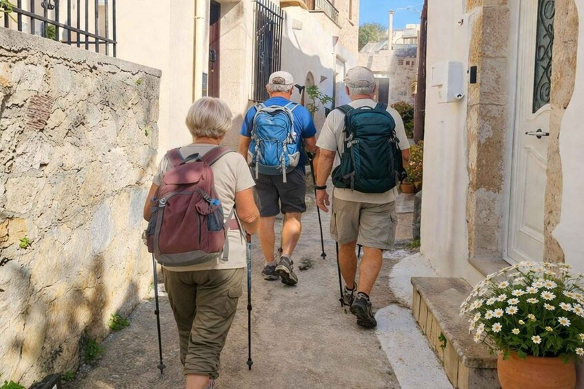 A narrow alley with stone walls, a man with a backpack, and a woman with a walking stick. 2