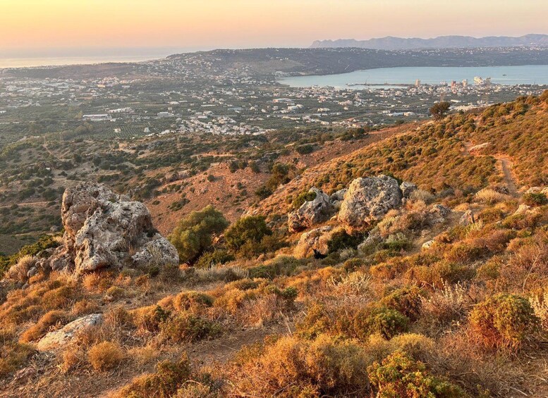 A coastal landscape with rocky terrain and a view of a city in the distance. 3