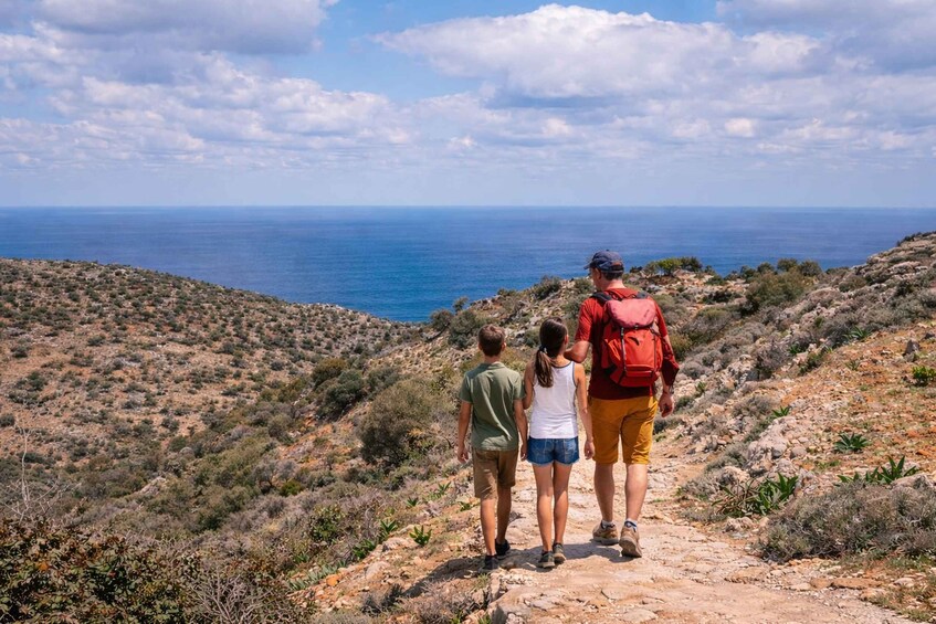 A family walking on a rocky trail overlooking a coastal landscape. 5