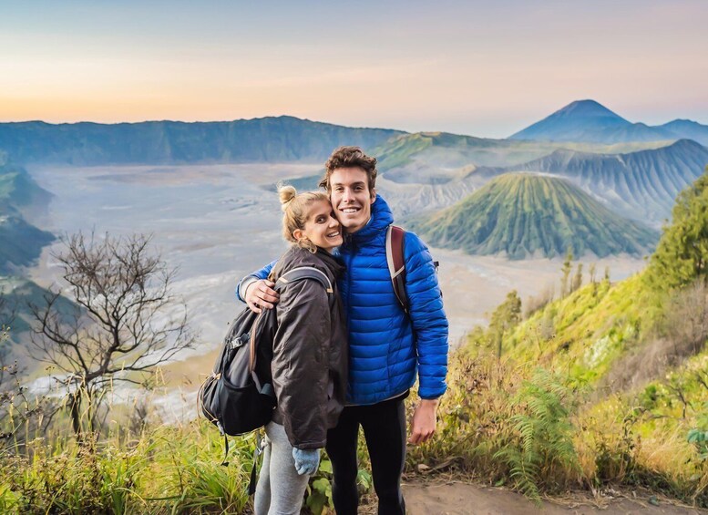 A couple embracing on a mountain trail with a panoramic view of a volcanic landscape. 1