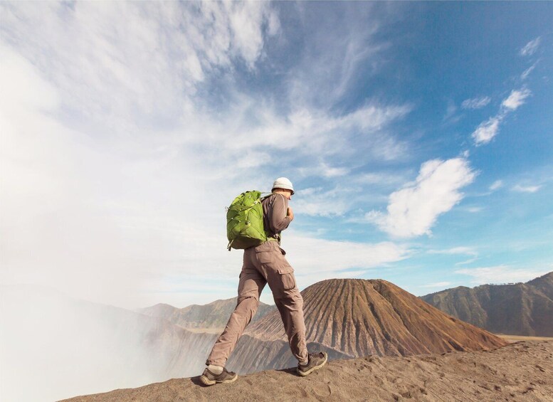 A hiker with a large green backpack on a mountain peak. 5