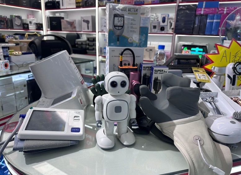 A robot, a blood pressure monitor, and a fast charger on a table in a store. 1