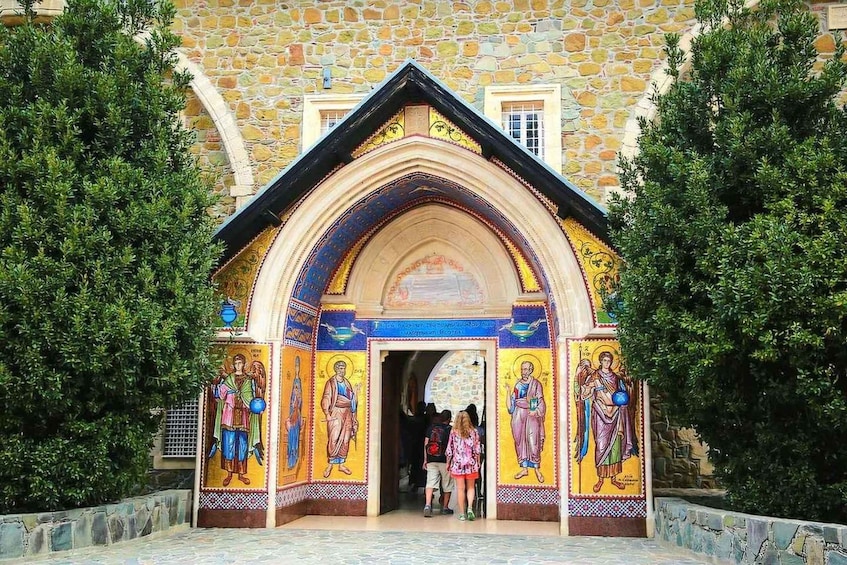 A church entrance with colorful mosaics and stone walls. 1