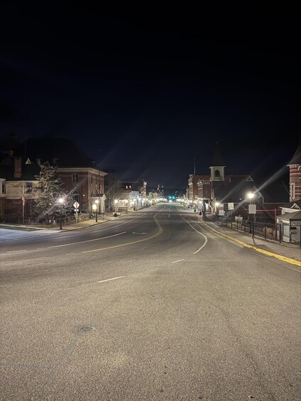 A nighttime street with buildings, streetlights, and a speed limit sign. 3