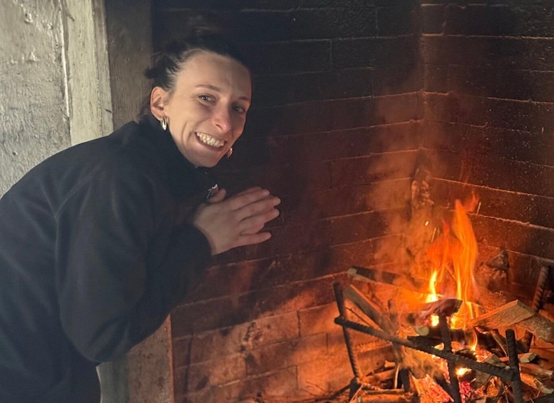A person standing near a fireplace with a fire burning. 5
