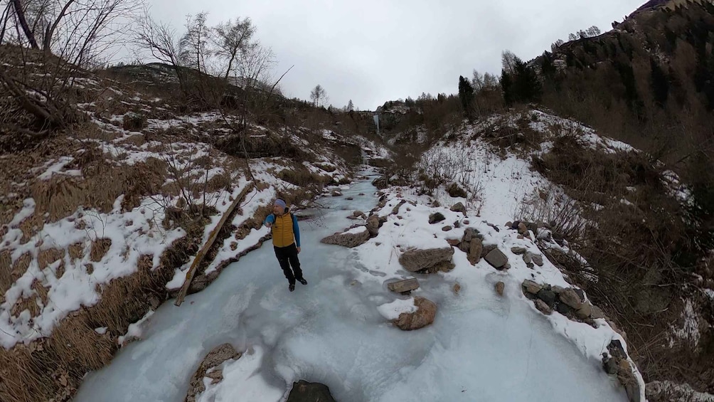 A person hiking on a snow-covered path with rocks and sparse vegetation. 3