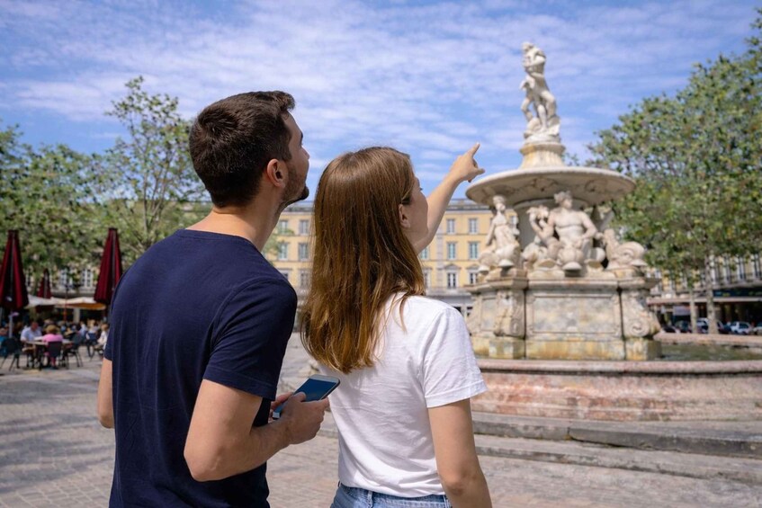 A couple standing in front of a fountain with a statue, with buildings and trees in the background. 5