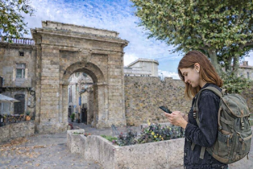 A person with a backpack standing in front of an old stone archway. 2