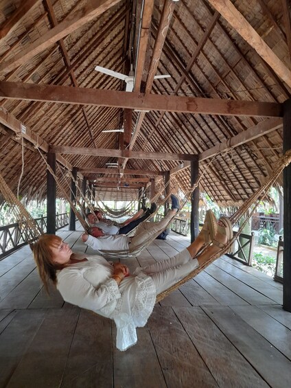 A person relaxing in a hammock under a wooden structure with a thatched roof. 4