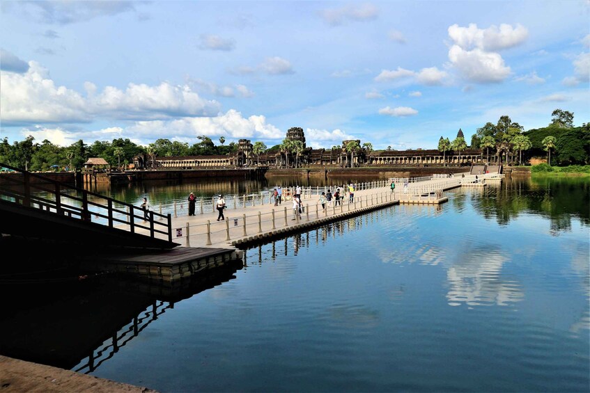 A calm river with a bridge, a dock, and a temple complex in the background. 1