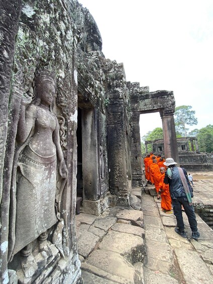 Ancient stone carvings, a partially ruined structure, and a group of people in orange robes. 3