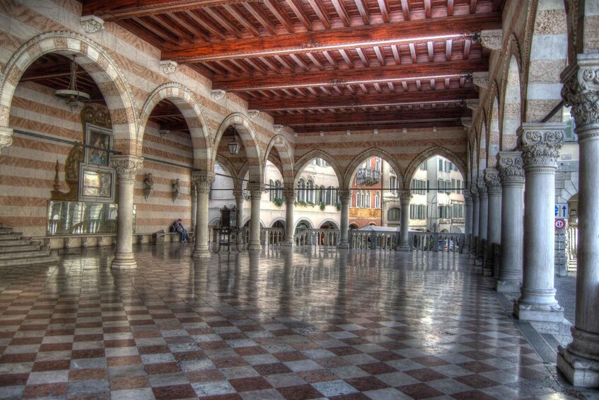 An indoor courtyard with checkered flooring, arches, and columns. 3