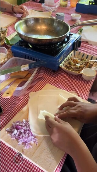 A person preparing food on a table with a frying pan, cutting board, and various ingredients. 5