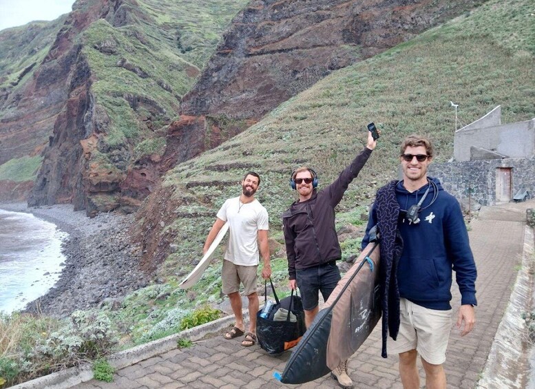 Three people with surfboards walking along a coastal path with cliffs. 4