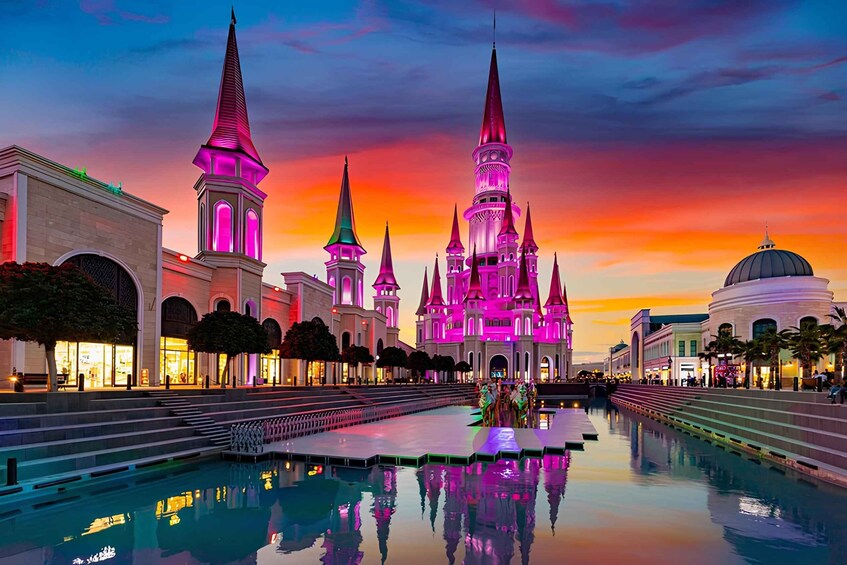 A brightly lit castle with multiple spires and a large dome, reflecting in a pool at sunset. 1