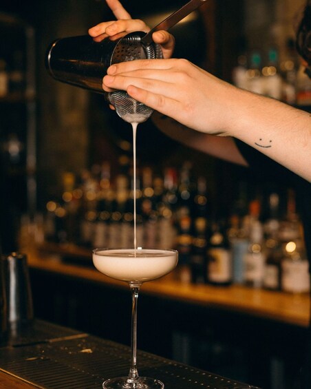 A bartender pouring a drink into a martini glass. 2