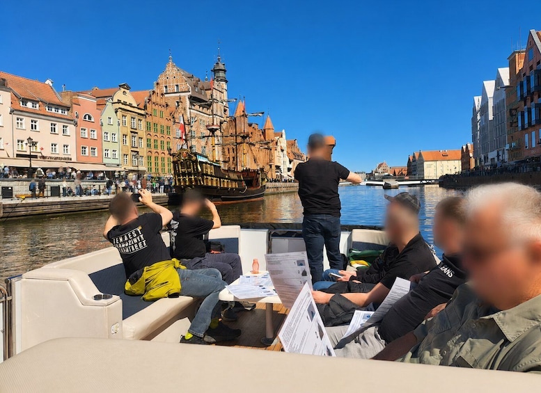A boat tour with passengers, a historic building, and a river. 2