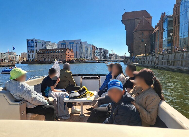A group of people on a boat in a canal with buildings in the background. 3