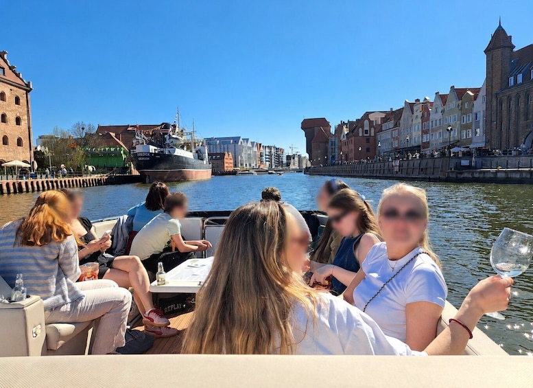 A group of people on a boat, a river, and buildings along the riverbank. 1
