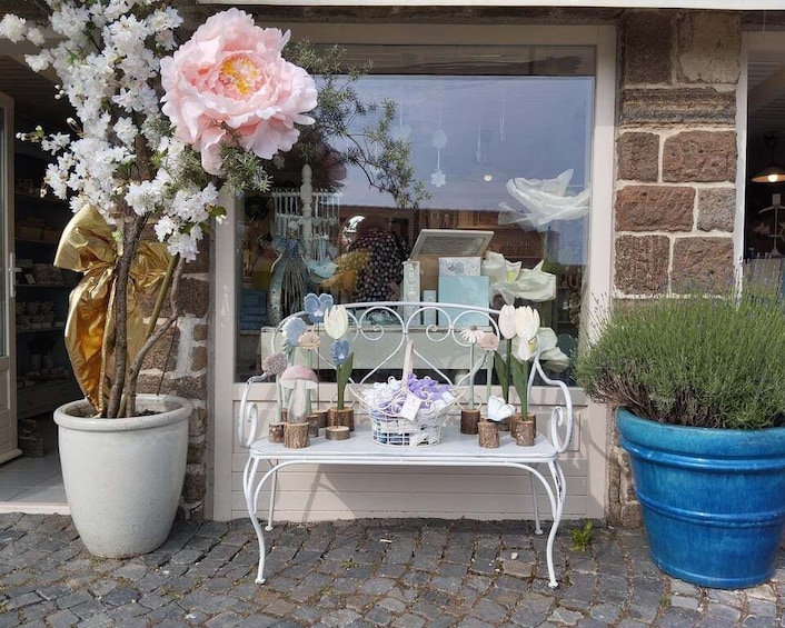 A storefront with a display of flowers and a bench outside. 1