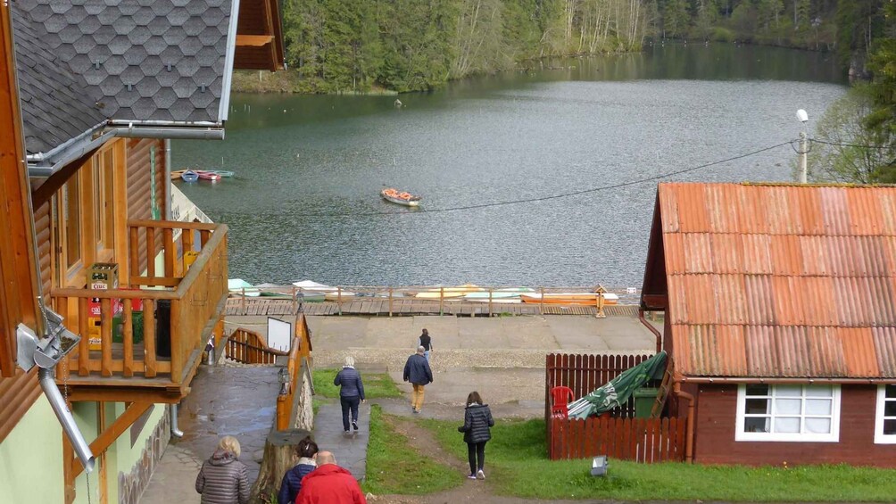 A lake with boats, a wooden dock, and people walking along the shore. 2