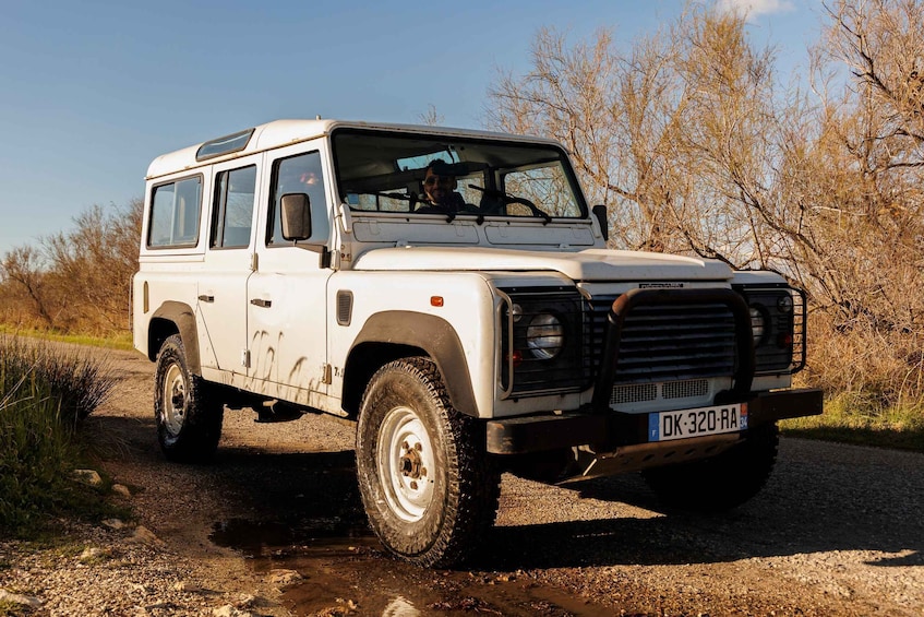 A white off-road vehicle on a gravel path with trees in the background. 3