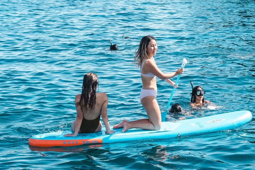 Three people on a blue paddleboard in the water. 3