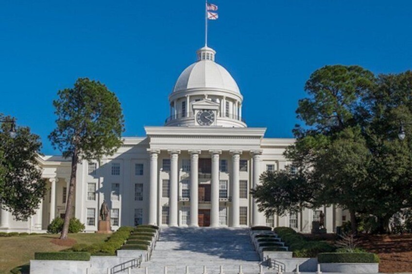 A large white building with a dome and columns, a flag, and a flagpole. 4