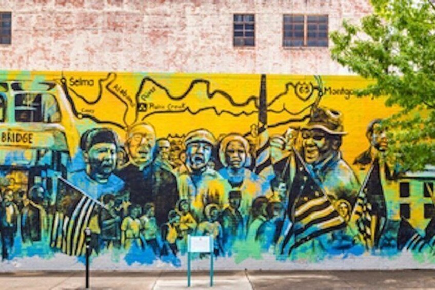 A mural with people and text on a building wall. 2