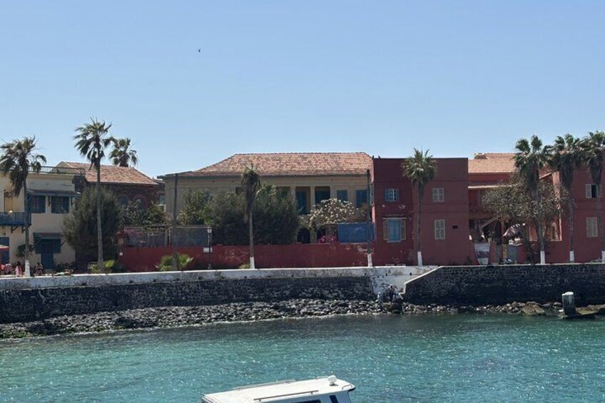 A coastal town with buildings, palm trees, and a clear blue sea. 1