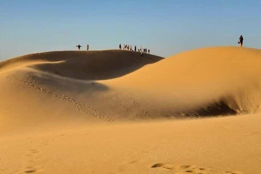 Sand dunes with people standing on top. 5