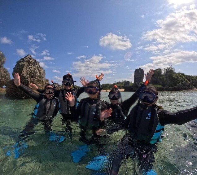 A group of people snorkeling in clear water with rocky formations in the background. 3
