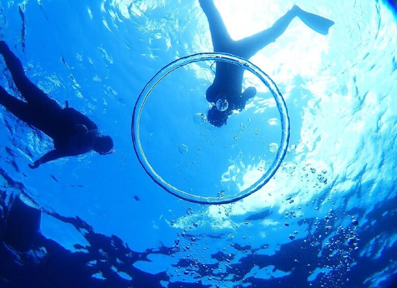 A diver swimming underwater with bubbles and a circular object. 5