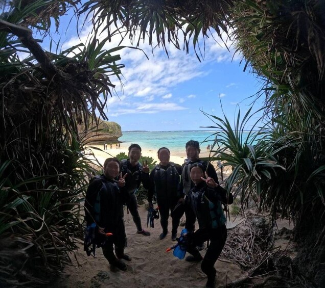 A group of divers in a natural setting with a beach and ocean in the background. 1