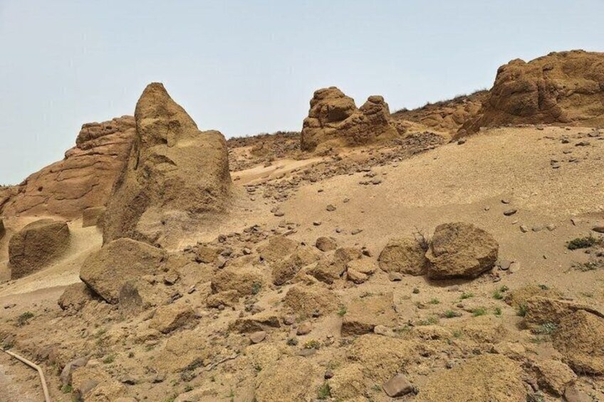 A rocky desert landscape with prominent rock formations and sparse vegetation. 2