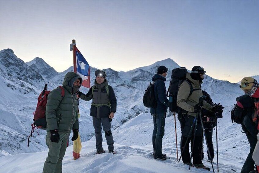 A group of hikers on a snowy mountain with a flag. 2
