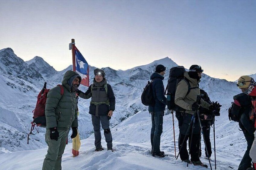 A group of hikers on a snowy mountain with a flag. 2