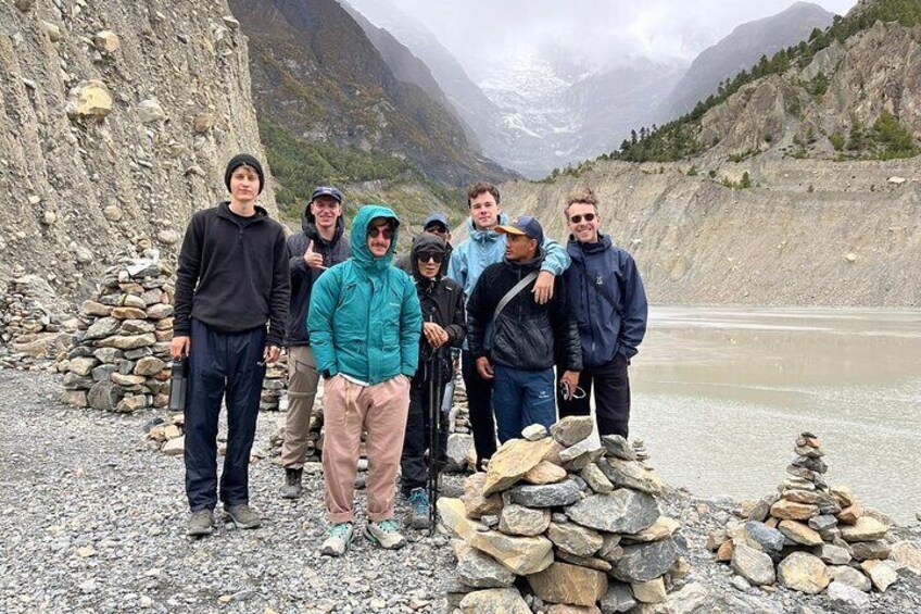 A group of people standing by a river with a mountainous backdrop. 5