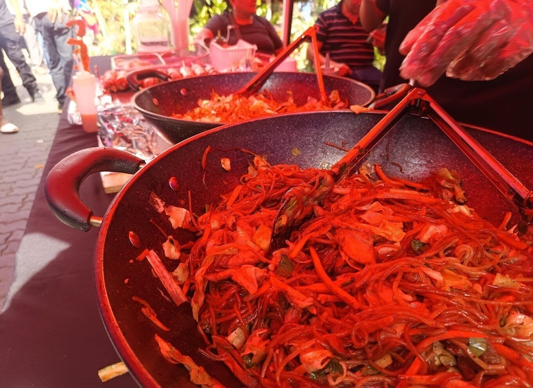 A street food stall with a large wok filled with stir-fried vegetables and shrimp. 4
