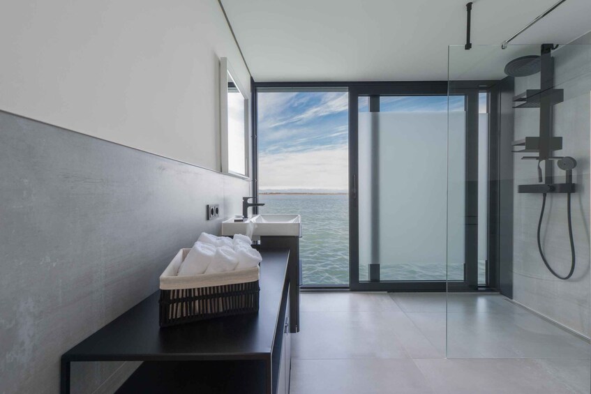 A modern bathroom with a large window overlooking a body of water. 2